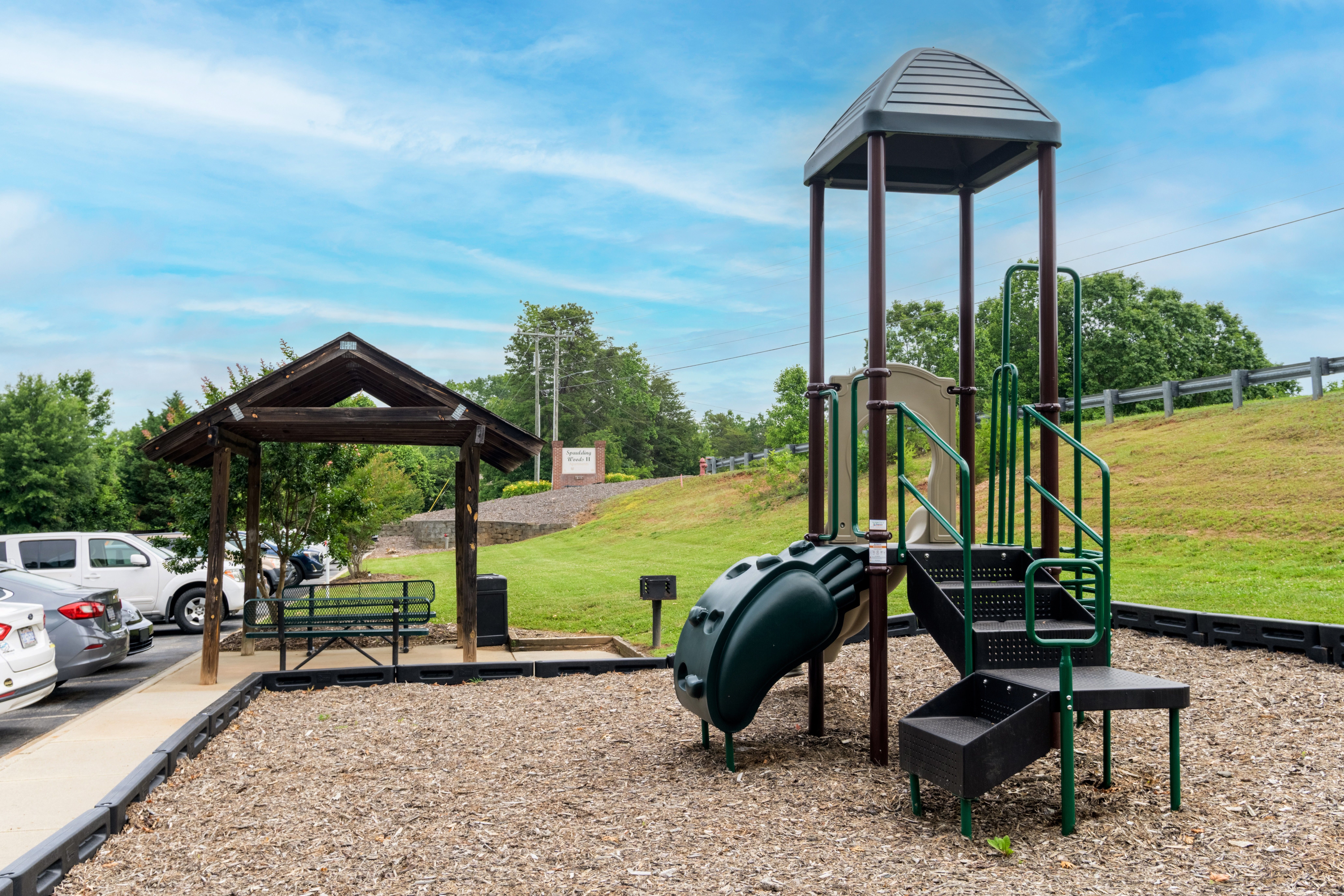 A playground with a green slide and a wooden structure.,A playground with a green slide and a wooden structure.